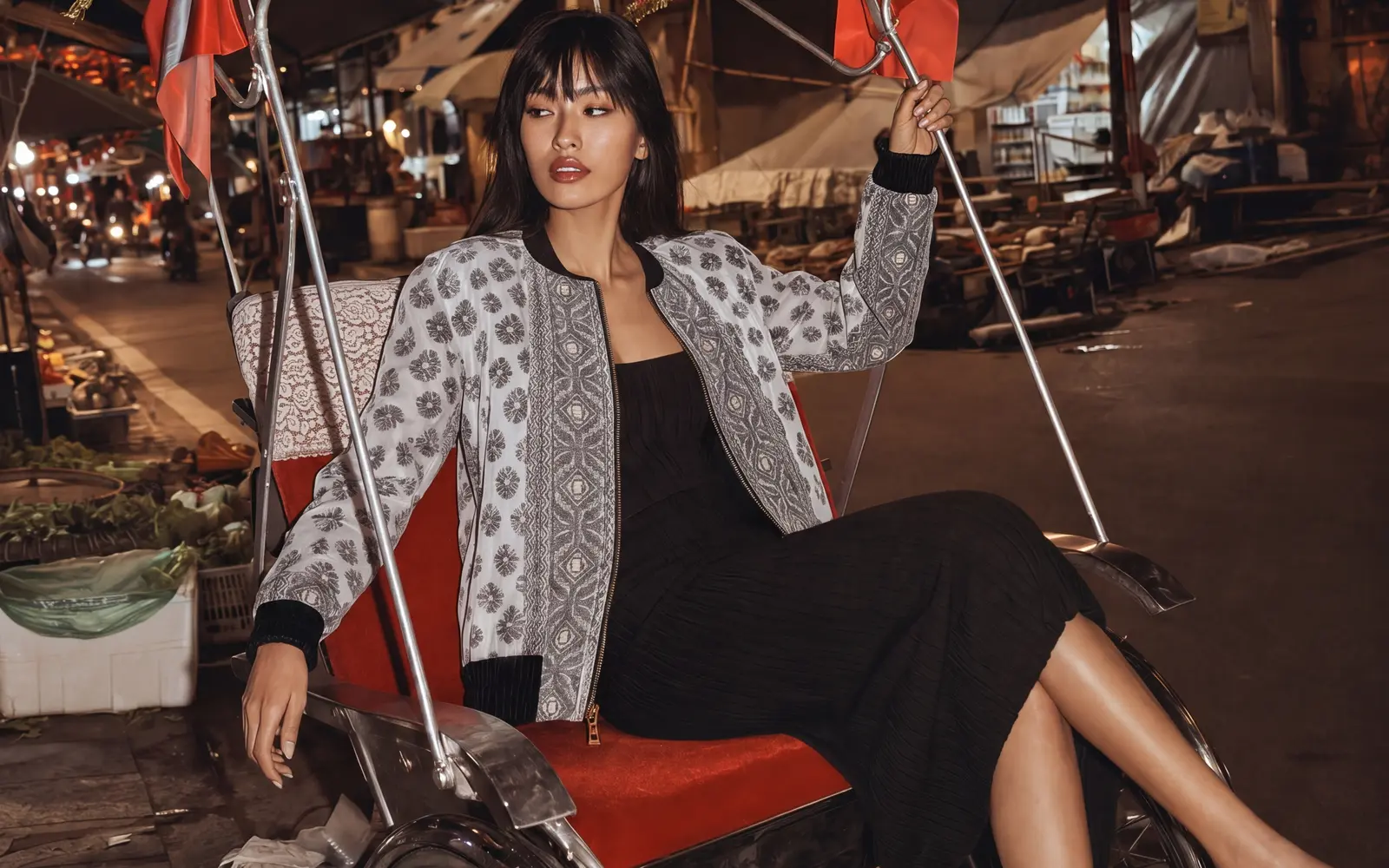 Model in a patterned jacket sitting in a painted rickshaw